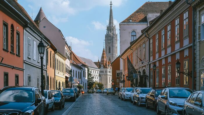 European netizens correcting common mistaken facts about their countries, featuring a historic street with cars and a church tower.