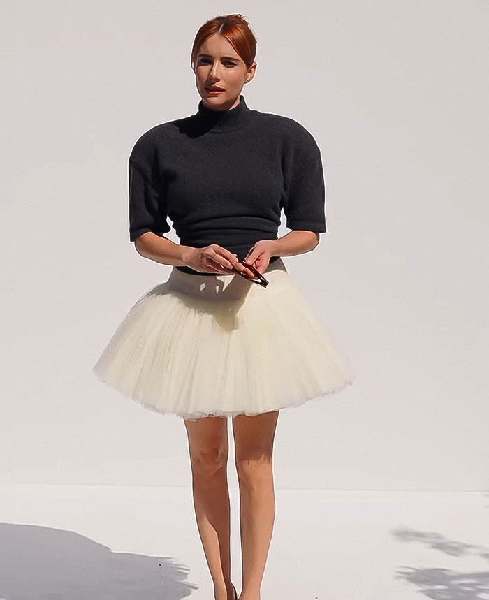 Emma Roberts in a black top and white tutu skirt, holding a phone, relating to Matthew McConaughey viral clip scene. Emma Roberts in a black top and white tutu skirt, holding a phone, relating to Matthew McConaughey viral clip scene.