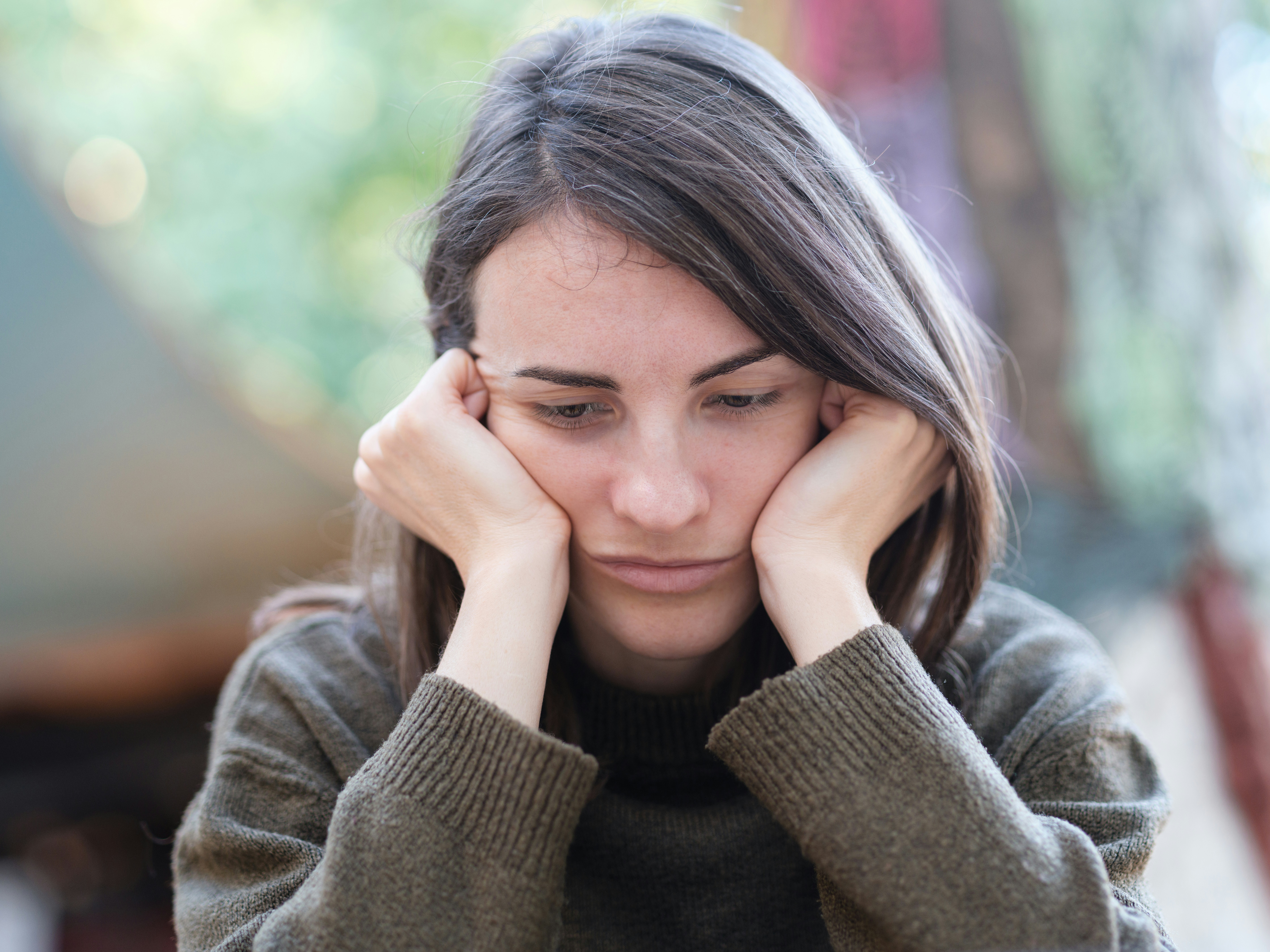 Young woman with sad expression resting face on hands, representing stereotypical American bride emotions Young woman with sad expression resting face on hands, representing stereotypical American bride emotions