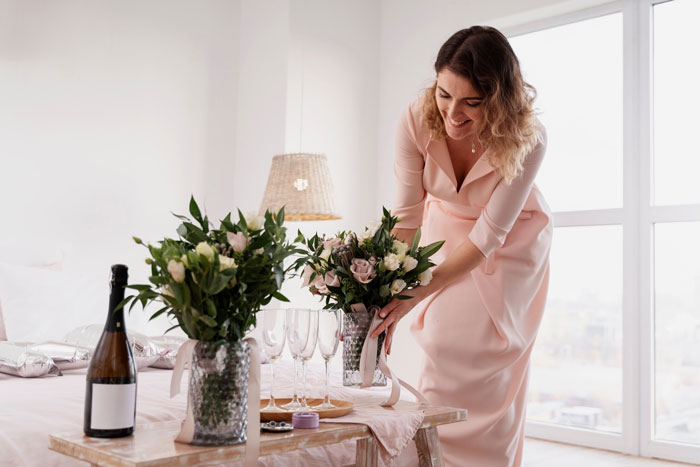 Woman arranging flowers on a table, representing mother of ring bearer shocked about being left off guest list despite help and RSVP. Woman arranging flowers on a table, representing mother of ring bearer shocked about being left off guest list despite help and RSVP.