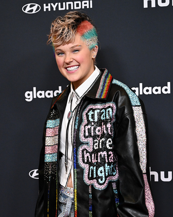 Person with colorful short hair wearing a sequined jacket at an event, related to famous lesbians boyfriend trend discussion. Person with colorful short hair wearing a sequined jacket at an event, related to famous lesbians boyfriend trend discussion.