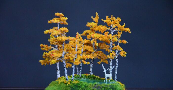 Miniature world featuring an enchanted forest with vibrant autumn trees and a small white deer figure.