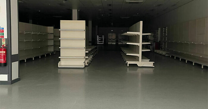 Empty retail store with vacant shelves and dim lighting, depicting an eerie liminal space atmosphere.