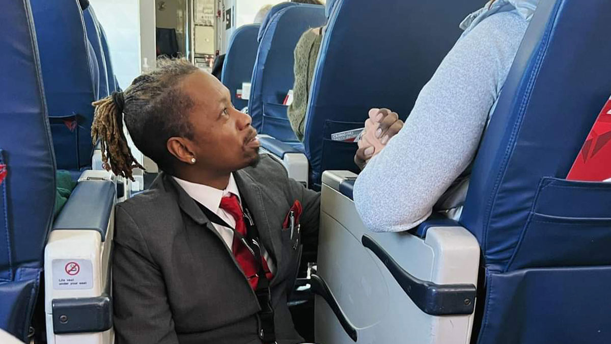 Flight attendant comforting nervous passenger on airplane, showing support for fear of flying during the flight.