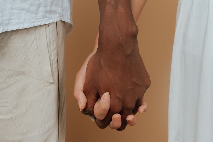 Close-up of two people holding hands, symbolizing a good trend slowly disappeared in relationships and connections.