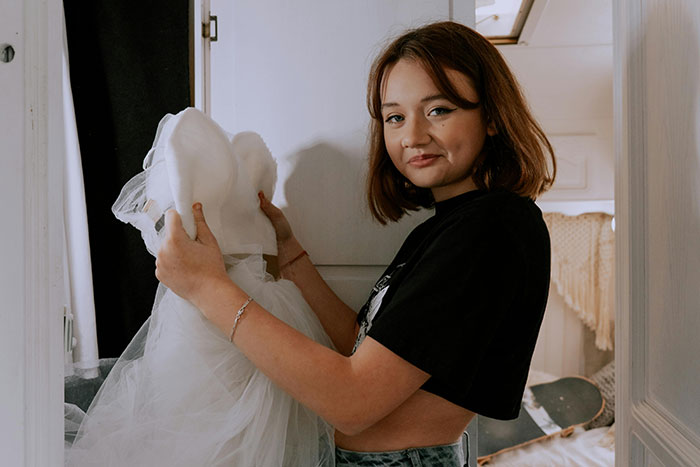 Bride holding a wedding dress indoors, reflecting on groom-to-be's cold feet jokes before their upcoming wedding. Bride holding a wedding dress indoors, reflecting on groom-to-be's cold feet jokes before their upcoming wedding.