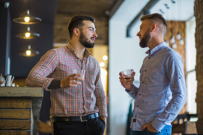 Two men chatting and holding drinks in a modern cafe, representing control over big money projects and career success. Two men chatting and holding drinks in a modern cafe, representing control over big money projects and career success.