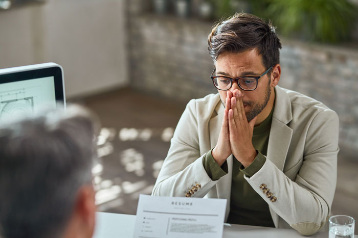 Man in glasses and beige jacket contemplating during a job interview, reflecting on controlling big money projects. Man in glasses and beige jacket contemplating during a job interview, reflecting on controlling big money projects.