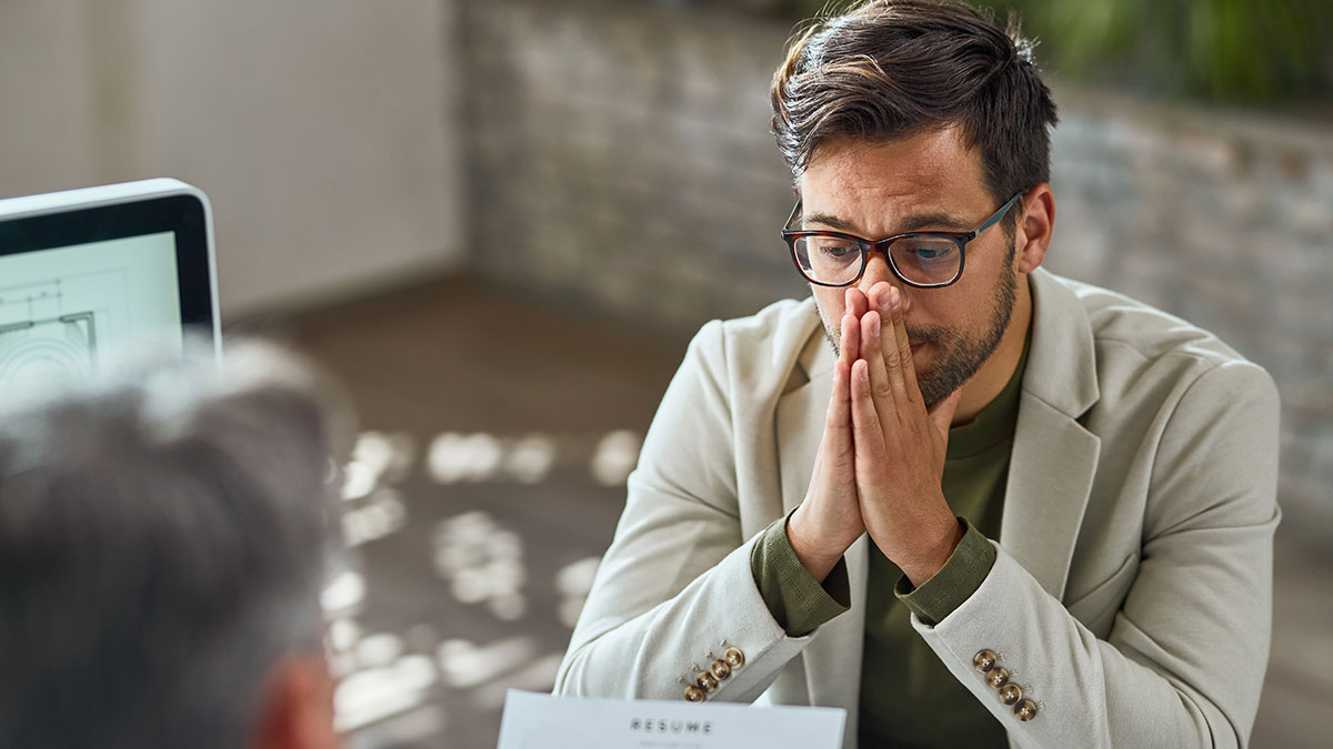 Man in glasses contemplates while discussing big money projects in a formal office setting.