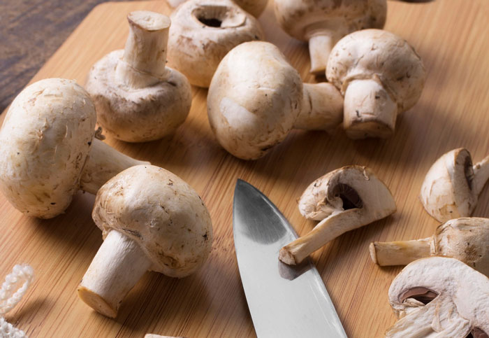 Fresh mushrooms and a kitchen knife on a wooden cutting board, highlighting fiber’s role in removing cancer-causing chemicals. Fresh mushrooms and a kitchen knife on a wooden cutting board, highlighting fiber’s role in removing cancer-causing chemicals.