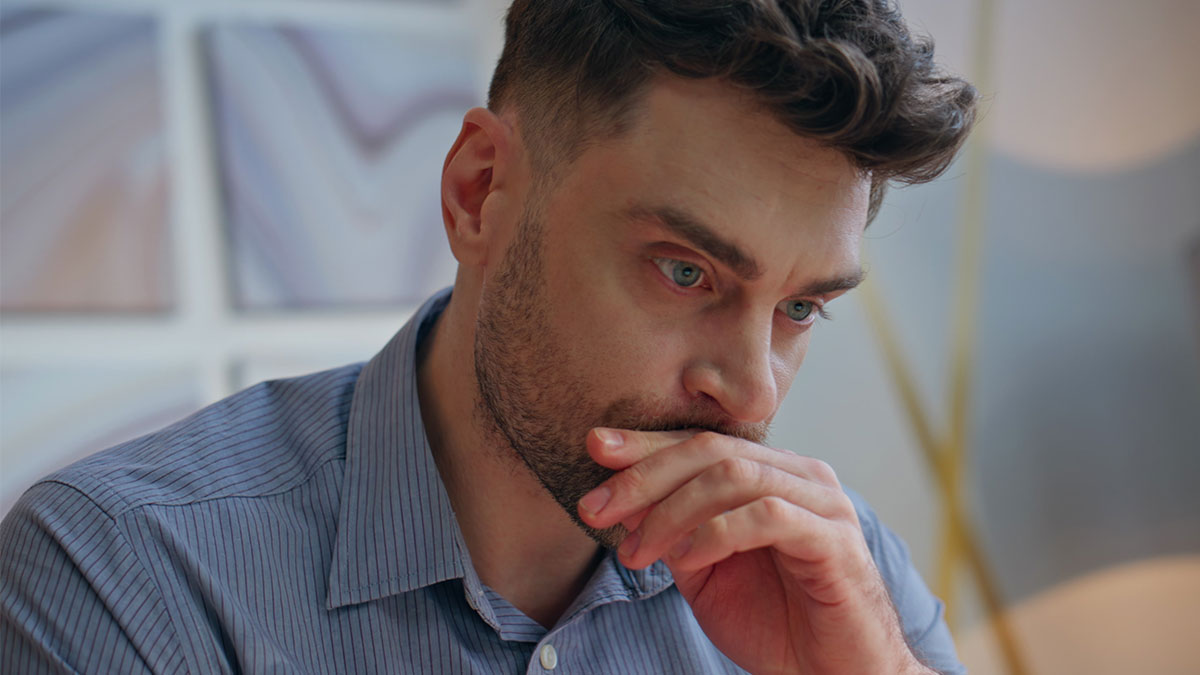 Man looking worried while thinking about needing niece to watch his 11-year-old son during emergency.