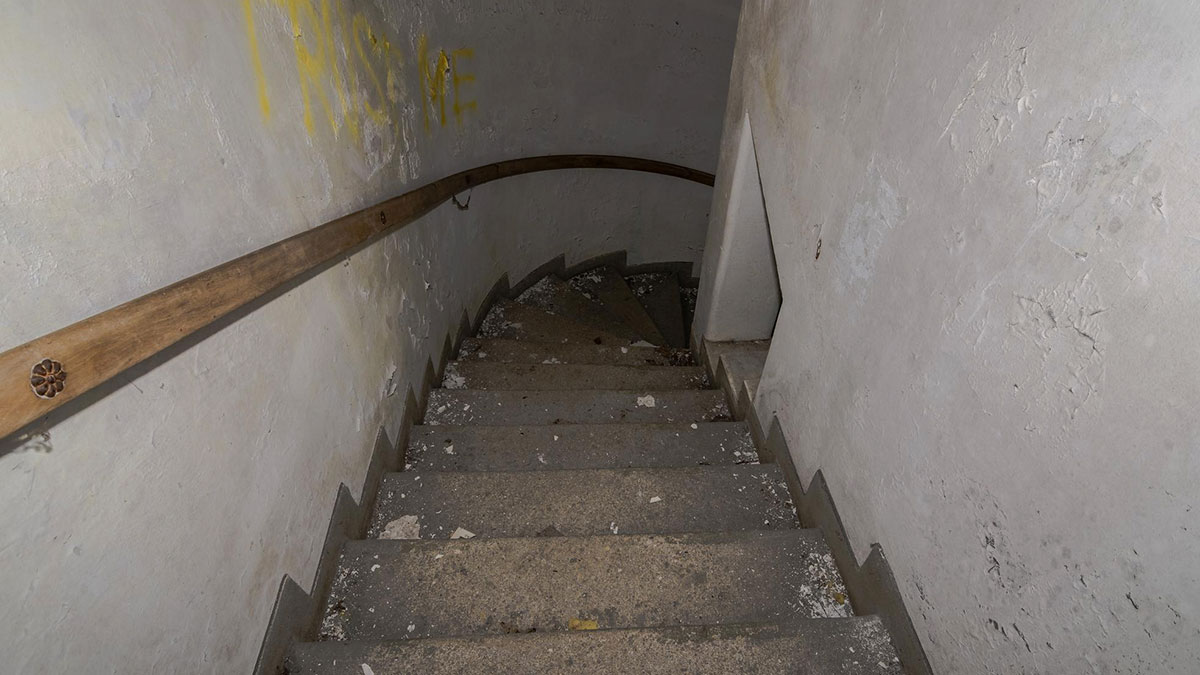 Worn stone stairs with wooden handrail leading down to a 400-year-old burial vault discovered during church restoration.