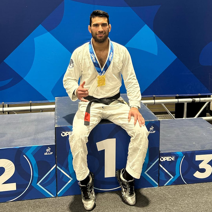 Male Jiu-Jitsu black-belt trainer wearing a medal sitting on the winner’s podium after competition event. Male Jiu-Jitsu black-belt trainer wearing a medal sitting on the winner’s podium after competition event.