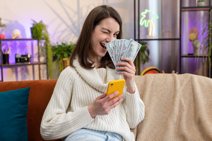 Woman holding cash and phone, winking with a playful expression, representing inheritance dispute and friendship conflict.