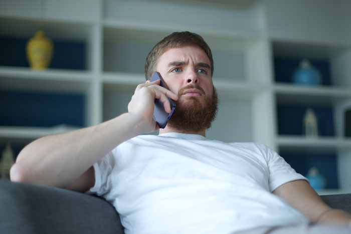 Man with beard looking upset while talking on phone, depicting a guy turning psycho on friends after crush chose friend. Man with beard looking upset while talking on phone, depicting a guy turning psycho on friends after crush chose friend.