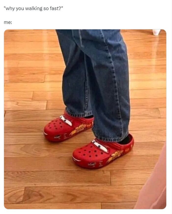 Person wearing red Lightning McQueen themed Crocs standing on wooden floor in a funny meme about walking fast.