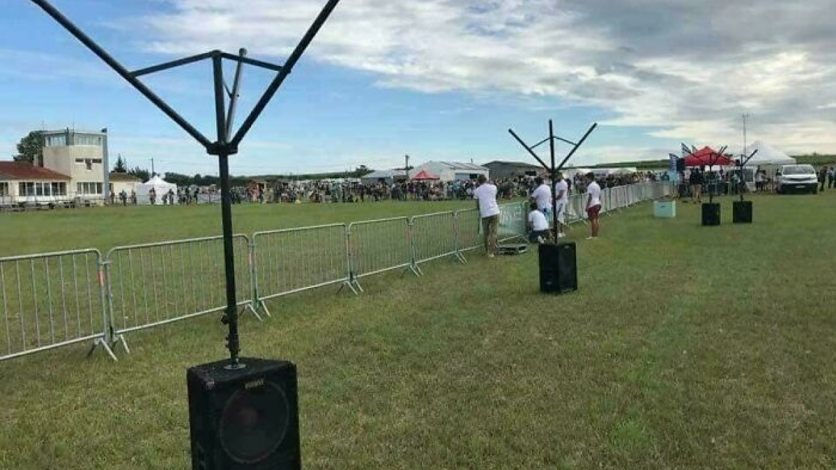 Speakers set up outdoors on a field with empty microphone stands, showing a technology disaster setup at an event.