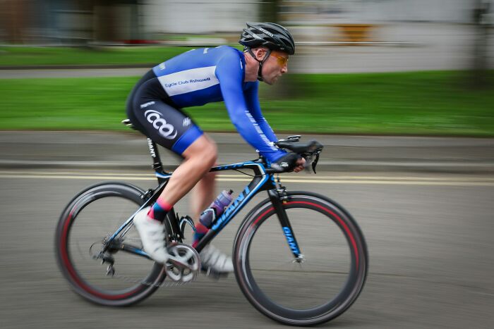 Cyclist in blue gear riding a road bike at high speed, illustrating active profession and dynamic lifestyle imagery.