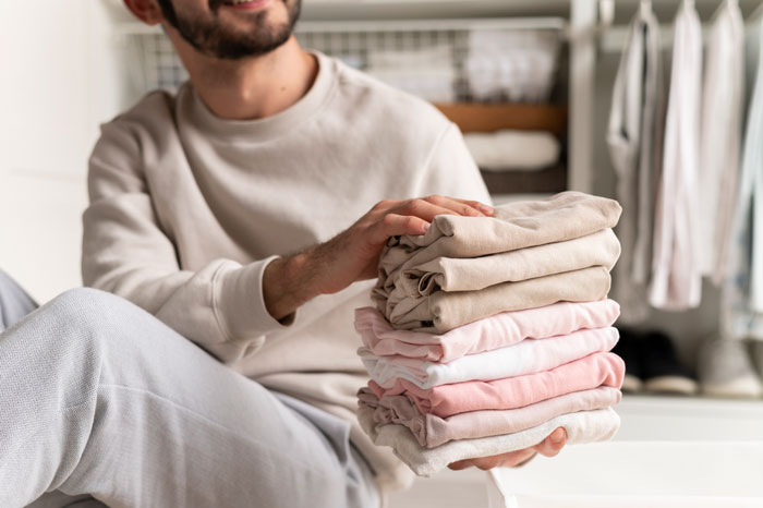 Man folding clothes at home, smiling and showing calm girlfriend behaviour change in relationship through daily routines.