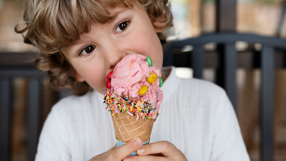 Child enjoying colorful candy-topped ice cream, highlighting boomer relatives undermining kids' healthy habits.