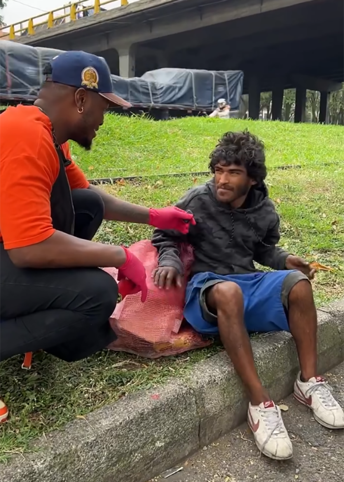 Barber wearing gloves talks with homeless man outdoors before viral makeover sparks controversy over potential model downgrade. Barber wearing gloves talks with homeless man outdoors before viral makeover sparks controversy over potential model downgrade.