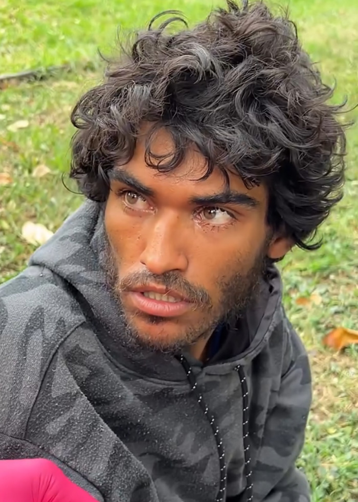 Homeless man with curly hair and beard sitting outdoors before a viral makeover and barber controversy. Homeless man with curly hair and beard sitting outdoors before a viral makeover and barber controversy.