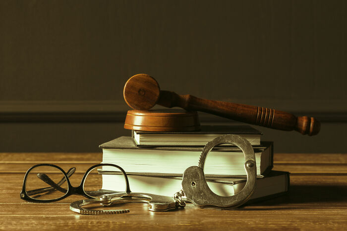 Gavel, handcuffs, and eyeglasses placed on books symbolizing local dangers and legal challenges in daily life.