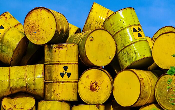Stack of rusty yellow barrels with radiation hazard symbols representing local dangers as a normal part of life.