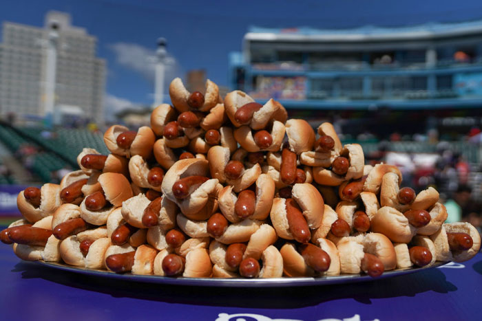 A large pile of hot dogs stacked on a tray at a stadium, highlighting concerns about human DNA in hot dogs.