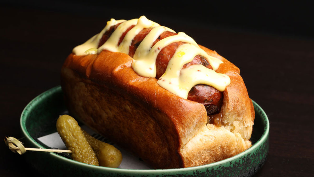 Hot dog with creamy mustard sauce on a plate, illustrating concerns about human DNA in hot dogs in food safety.