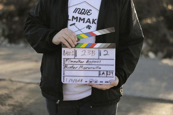 Person holding a film clapperboard outdoors, related to UK perspectives shared by various people in media.