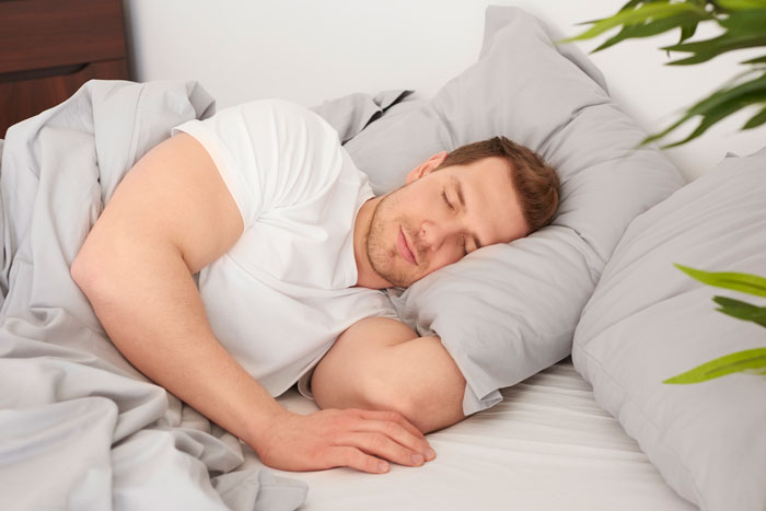 Husband enjoying lazy mornings lying peacefully in bed with gray bedding, illustrating uneven Sunday deal and sleep sacrifice. Husband enjoying lazy mornings lying peacefully in bed with gray bedding, illustrating uneven Sunday deal and sleep sacrifice.