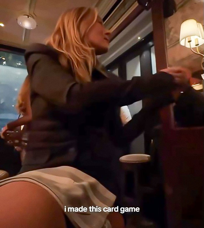 Woman in a dark jacket sitting at a table in a dimly lit room, related to pushy influencer rejected by Taylor Swift. Woman in a dark jacket sitting at a table in a dimly lit room, related to pushy influencer rejected by Taylor Swift.