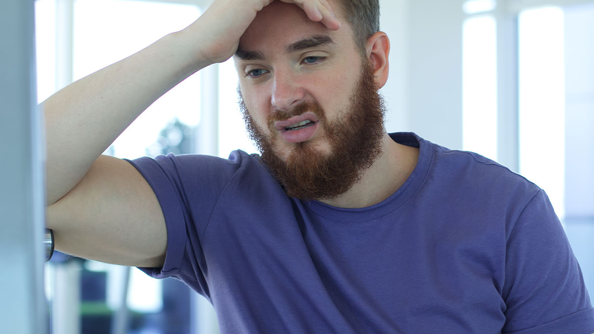 Frustrated man in gym wearing a purple shirt, showing annoyed gym moments that make running in the rain a better choice.