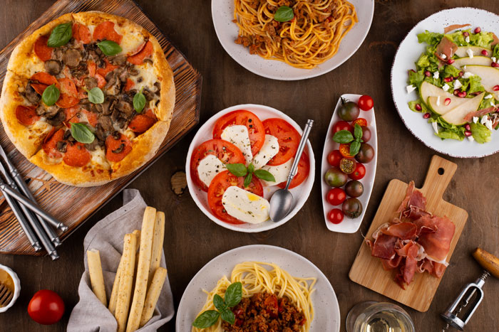 Italian friend visiting, table with pizza, spaghetti, caprese salad, prosciutto, and breadsticks showcasing Italian spices and cuisine. Italian friend visiting, table with pizza, spaghetti, caprese salad, prosciutto, and breadsticks showcasing Italian spices and cuisine.
