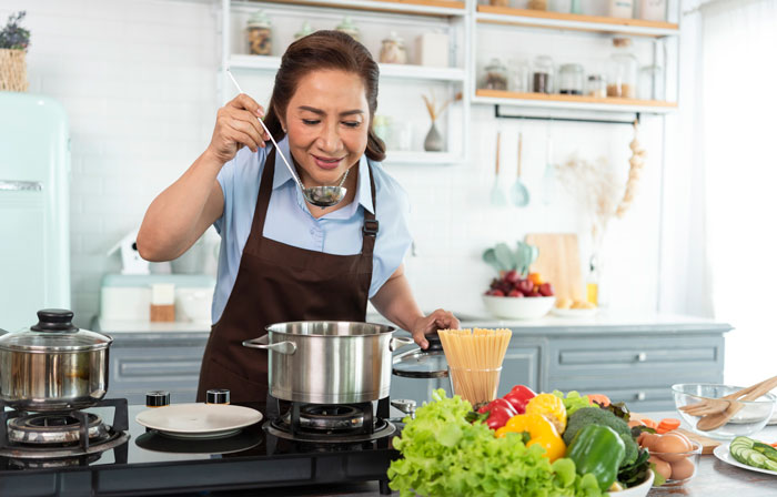 Woman cooking in kitchen, tasting food from pot, hosting hubby’s Italian friend, using spices and ingredients for meal. Woman cooking in kitchen, tasting food from pot, hosting hubby’s Italian friend, using spices and ingredients for meal.