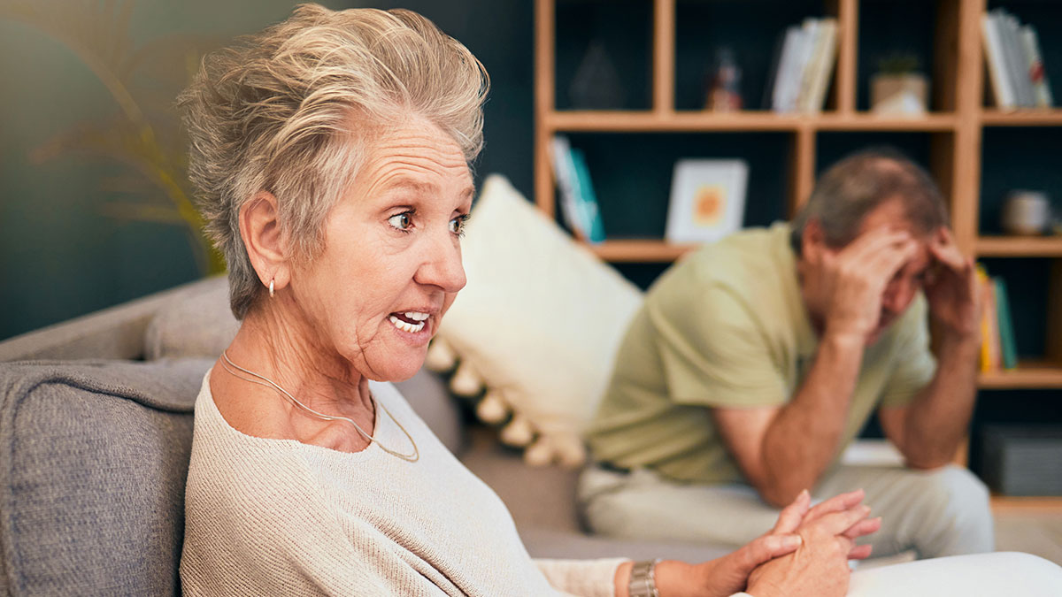 Woman hosting hubbyu2019s Italian friend, discussing spices and cappuccino after noon, while man looks stressed in background.