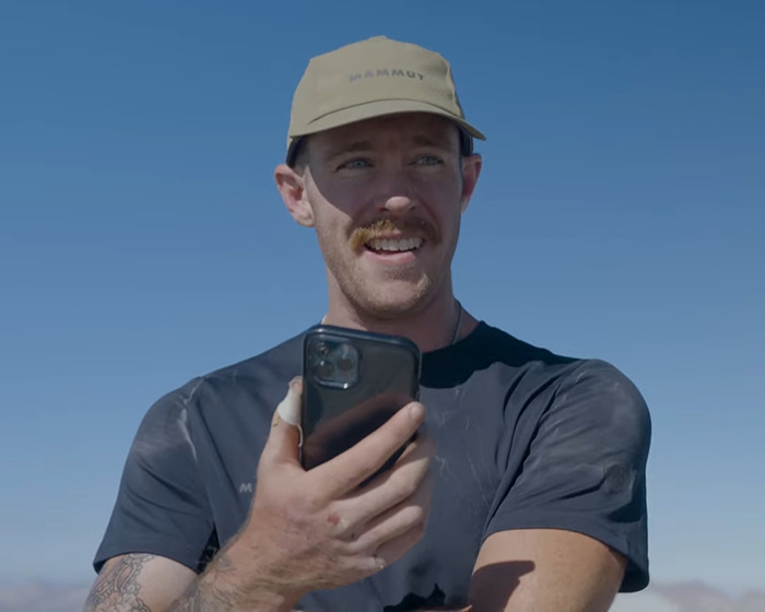 Man wearing beige cap and black shirt holding phone outdoors discussing Jiu-Jitsu trainer and beginner student injury settlement. Man wearing beige cap and black shirt holding phone outdoors discussing Jiu-Jitsu trainer and beginner student injury settlement.