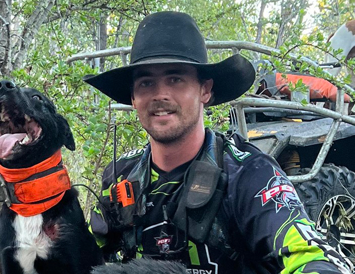 Man wearing a black cowboy hat with a dog in an outdoor forest setting, related to a misogynistic comment incident. Man wearing a black cowboy hat with a dog in an outdoor forest setting, related to a misogynistic comment incident.
