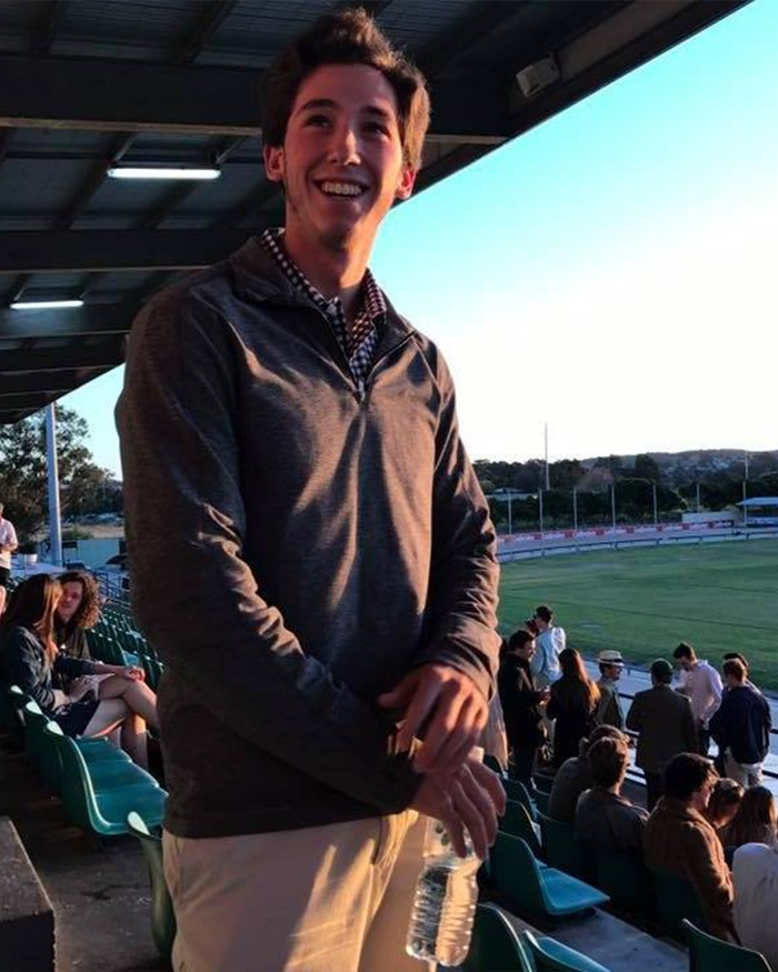Young man smiling and holding a water bottle at a sports stadium, related to honeymoon tragedy in ankle-deep water. Young man smiling and holding a water bottle at a sports stadium, related to honeymoon tragedy in ankle-deep water.