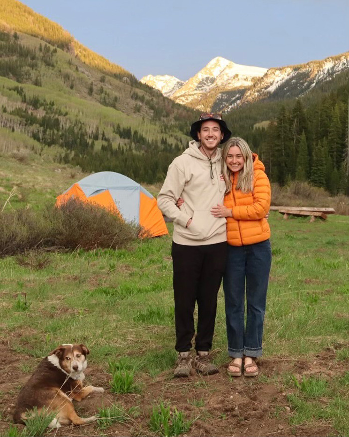 Newlyweds smiling outdoors near a tent with mountains in background during honeymoon before tragedy in ankle-deep water. Newlyweds smiling outdoors near a tent with mountains in background during honeymoon before tragedy in ankle-deep water.