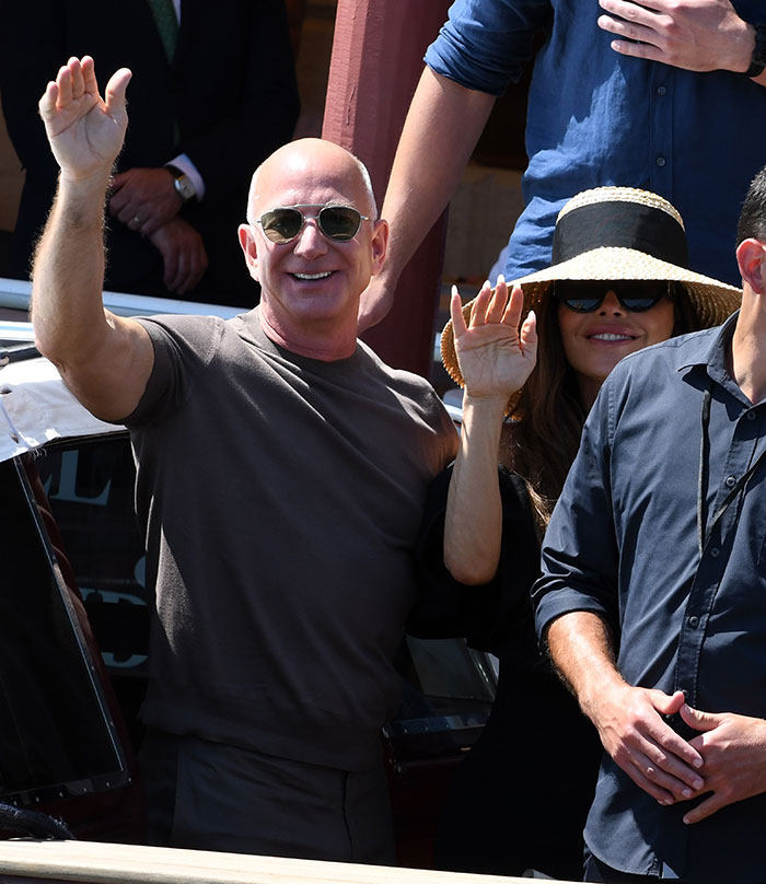 Jeff Bezos and Lauren Sánchez waving while attending a celebrity event after weekend wedding partying. Jeff Bezos and Lauren Sánchez waving while attending a celebrity event after weekend wedding partying.