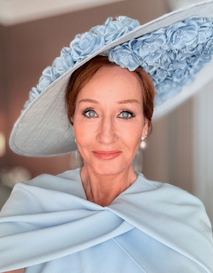 Close-up of a woman with blue eyes wearing a large pale blue floral hat and matching outfit in a softly lit room. Close-up of a woman with blue eyes wearing a large pale blue floral hat and matching outfit in a softly lit room.