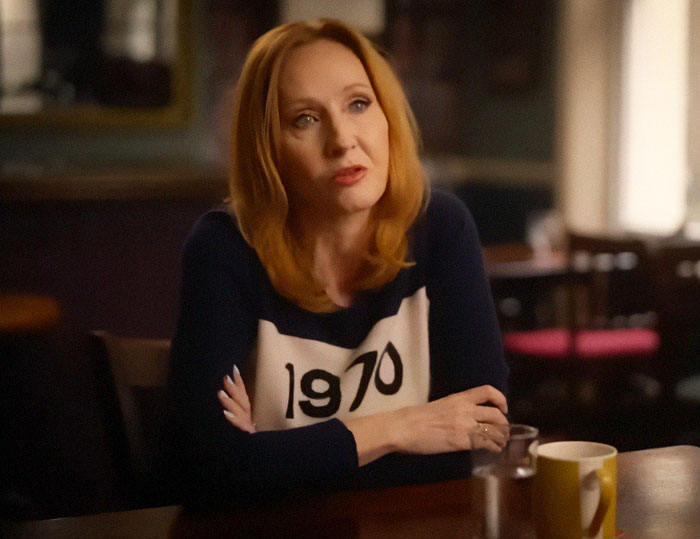 Author J.K. Rowling seated at a table indoors, engaged in conversation related to Harry Potter fans. Author J.K. Rowling seated at a table indoors, engaged in conversation related to Harry Potter fans.