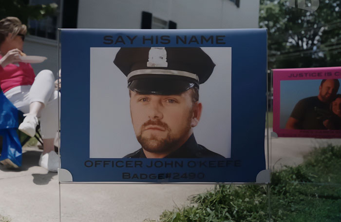 Memorial sign for Officer John O'Keefe with the phrase Say His Name, related to Karen Read trial and slaying controversy. Memorial sign for Officer John O'Keefe with the phrase Say His Name, related to Karen Read trial and slaying controversy.