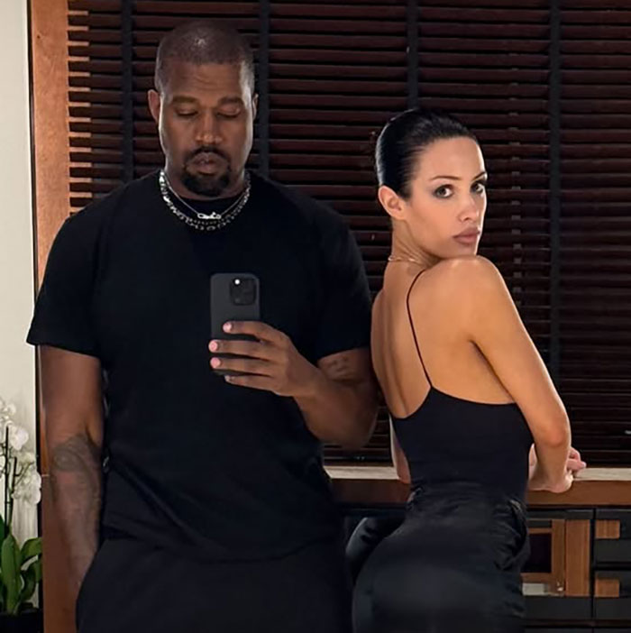 Kanye West and his wife Bianca Censori posing indoors, highlighting Bianca in a black outfit and sleek hairstyle. Kanye West and his wife Bianca Censori posing indoors, highlighting Bianca in a black outfit and sleek hairstyle.
