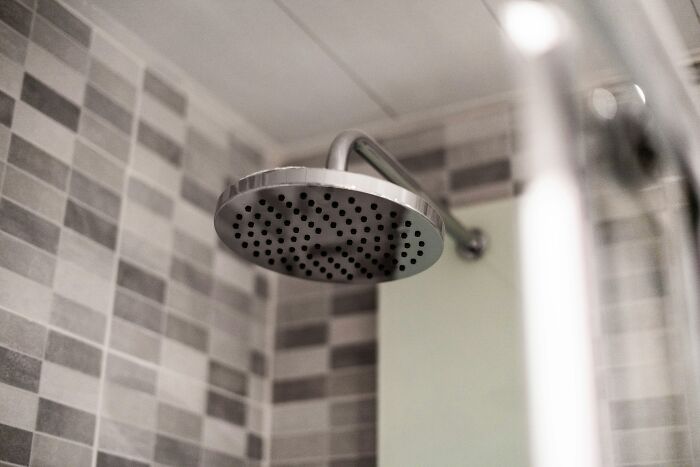 Showerhead mounted in a modern bathroom with gray tiled walls capturing a clean and minimalistic design.