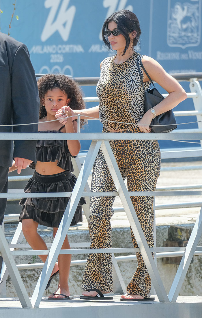 Celebrity in leopard print outfit and sunglasses walking with child, showcasing strung-out celebrity looks after weekend partying event. Celebrity in leopard print outfit and sunglasses walking with child, showcasing strung-out celebrity looks after weekend partying event.