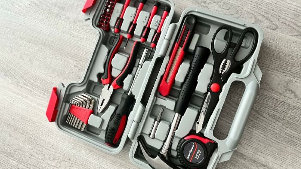 Compact tool kit with pliers, screwdrivers, hammer, scissors, and measuring tape for adulting starter pack essentials.