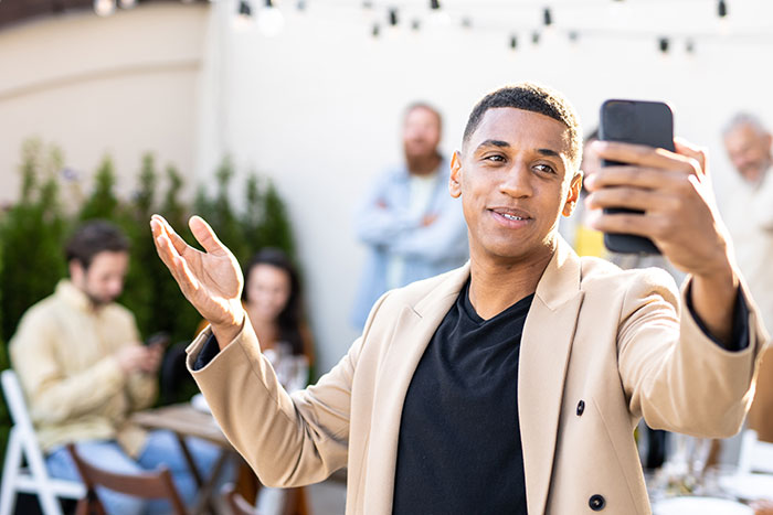 Young influencer marketing coworker takes a selfie confidently at an outdoor office gathering with blurred colleagues in background Young influencer marketing coworker takes a selfie confidently at an outdoor office gathering with blurred colleagues in background